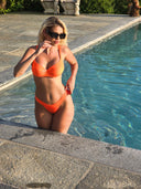     Maillot femme FUEGO avec teinte orange solaire et silhouette sculptée créant une allure glamour moderne et élégante sous le soleil